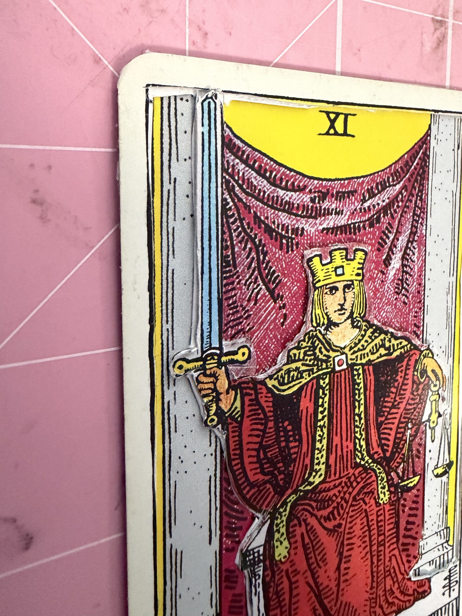 Close-up of Justice tarot card sword and figure with 3D layered handcrafted detail